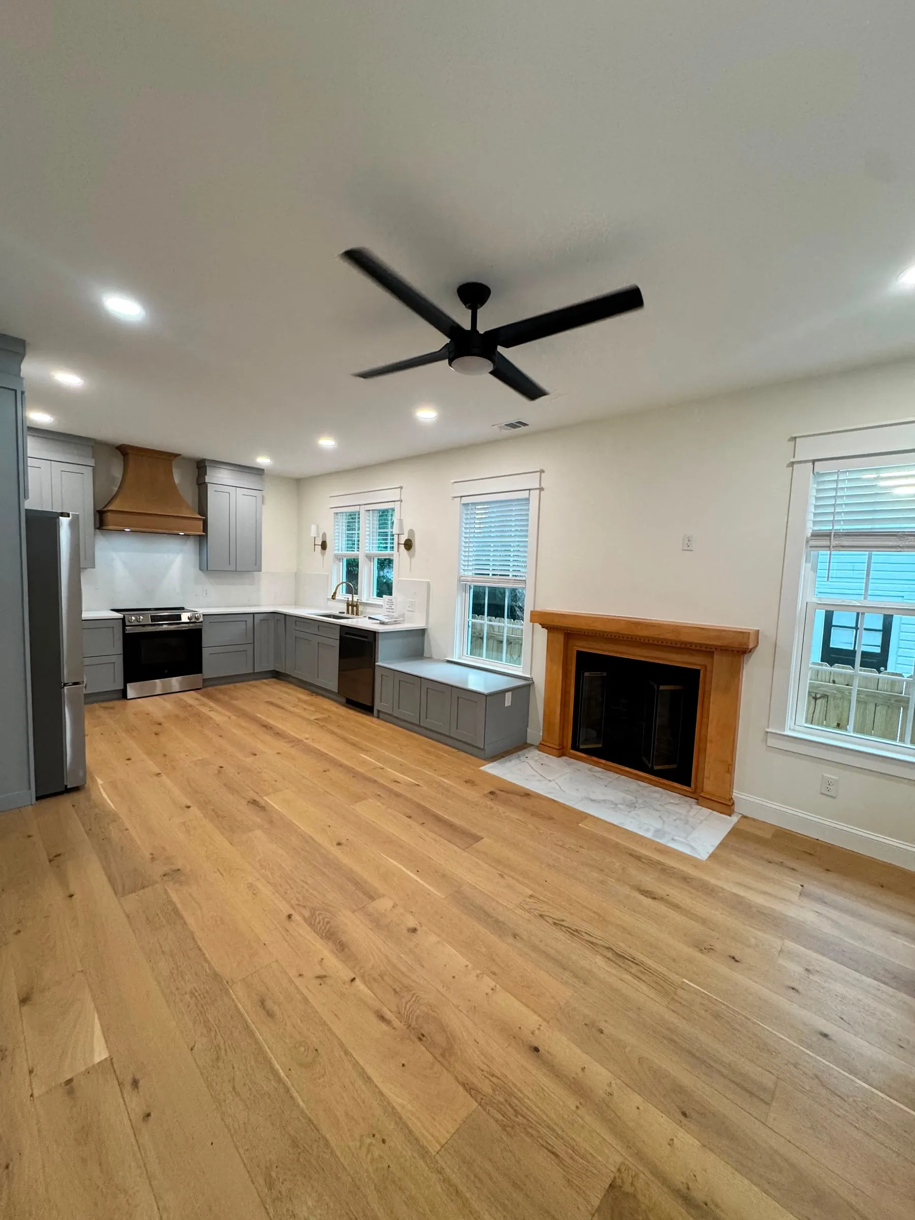 The open living room and kitchen after renovation, with white oak floors and a hearth set in marble.